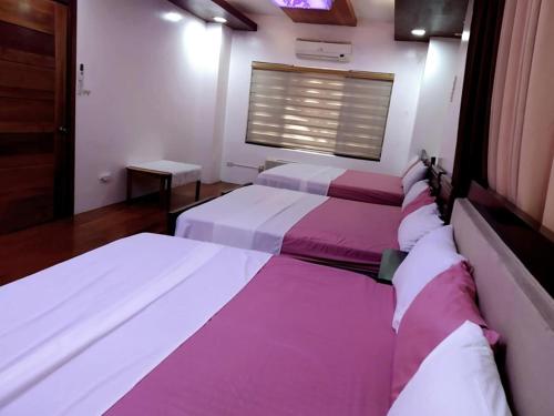 two beds in a room with purple and white sheets at Queen Isabel Private Villa and Events Place in Tagaytay