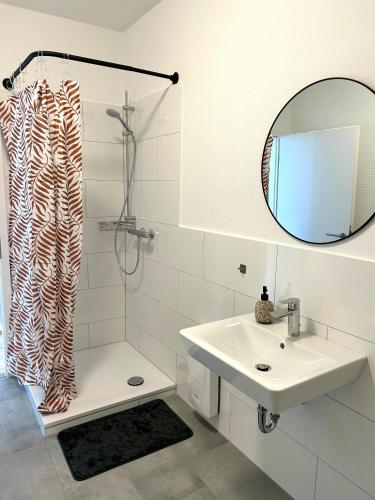 a bathroom with a sink and a shower with a mirror at Apartment über 3-Etagen genau im Zentrum! in Neumünster