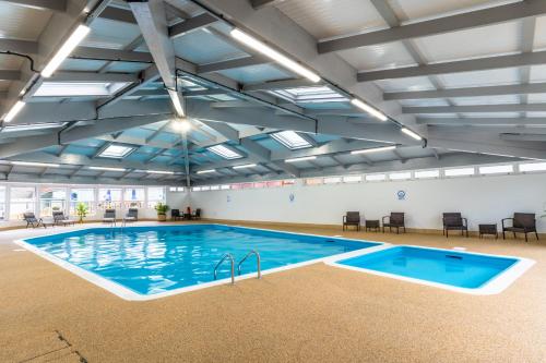 a large swimming pool with blue water in a building at Finest Retreats - Whitsand Bay Lodge in Torpoint