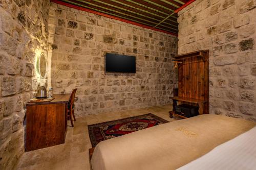 a bedroom with a bed and a desk and a tv at Latona Stone Palace in Nevsehir