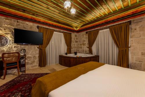 a bedroom with a bed and a tub and a tv at Latona Stone Palace in Nevsehir