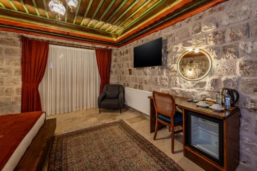 a room with a bed and a desk and a tv at Latona Stone Palace in Nevsehir