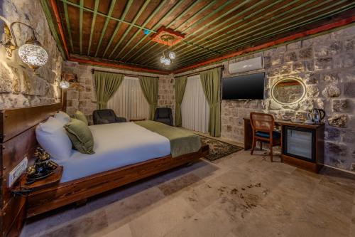 a bedroom with a bed and a desk and a tv at Latona Stone Palace in Nevsehir
