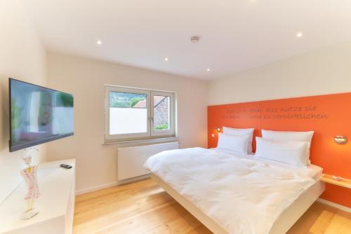a bedroom with a large bed with an orange wall at Oberhausen an der Nahe LIEBLINGSORT - Ferienappartements in Oberhausen