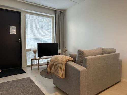 a living room with a couch and a television at Pramea Apartments Aallonharja 5 in Jyväskylä