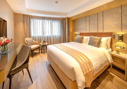a hotel room with a large bed and a desk at Grand Dragon Hotel in Macau