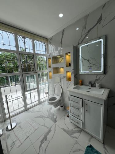 a bathroom with a sink and a toilet and a tv at La villa des anges in Kribi