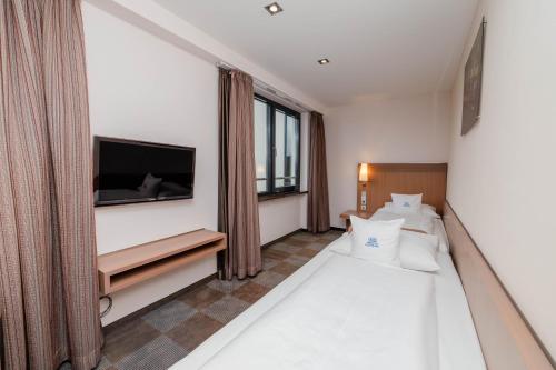 a bedroom with two beds and a flat screen tv at Parkhotel St.Leonhard in Überlingen