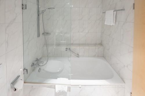 a white bathroom with a tub and a sink at Aspire AcarA Oldenburg, Trademark Collection by Wyndham in Oldenburg