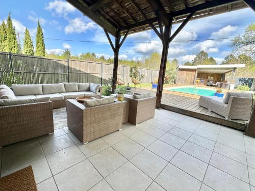 une terrasse avec un canapé et des chaises ainsi qu'une piscine dans l'établissement Grange rénovée au Calme, à Le Barp