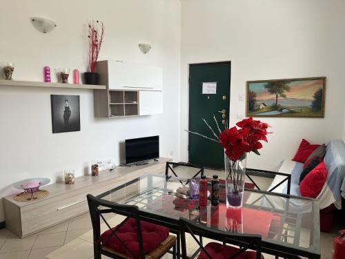 a living room with a glass table with red roses at appartamento genziane in Genova