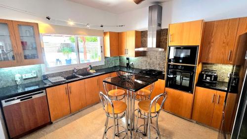 a kitchen with wooden cabinets and a island with bar stools at Suburban Family Villa in Limassol