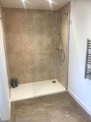 a shower with a glass door in a bathroom at The Mole Hill in Bransford