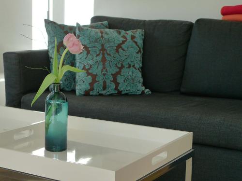 a vase with a pink flower on a table in front of a couch at Ferienwohnung Peterberg 22, 45qm in Kirchzarten