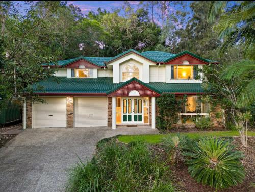 a house with a green roof and a driveway at Spacious home in Shailer Park in Tanah Merah