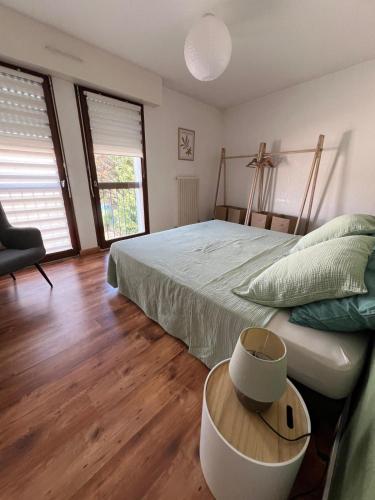 une chambre avec un lit, une table et des fenêtres dans l'établissement Le GINGKO ZEN EPINAL, à Épinal