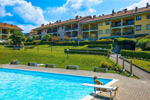 una mujer sentada en un banco junto a una piscina en Residenz Lagobello, en Germignaga