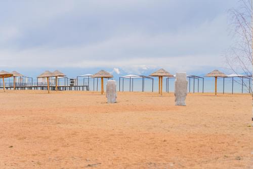 a row of straw umbrellas on a beach at Коттедж Иссык - Куль in Chon-Sary-Oy
