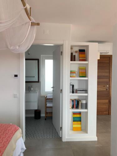a bedroom with a door open to a bathroom with a sink at Casa no Rio - River House in Vila Nova de Milfontes