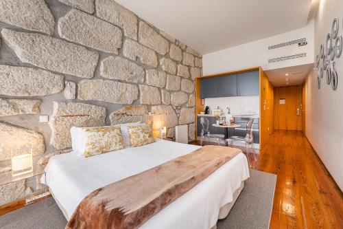 ポルトにあるGuestReady - Porto de Rio Residencesの石壁のベッドルーム1室(大型ベッド1台付)