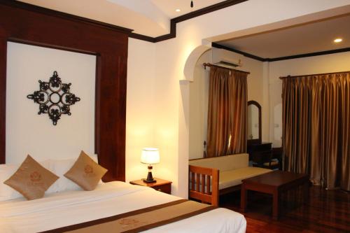 a bedroom with a bed and a desk and a chair at Lux Hotel in Luang Prabang