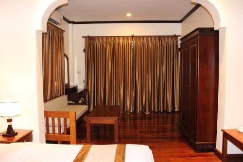 a bedroom with a bed and a desk and a window at Lux Hotel in Luang Prabang