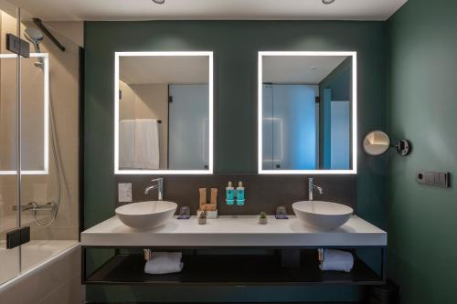 two sinks in a bathroom with two mirrors at Novotel Valencia Lavant in Valencia
