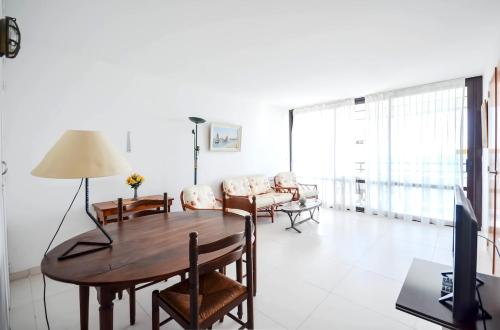 a living room with a wooden table and a television at Chez Alain - Confortable appartement et vue à couper le souffle in La Grande-Motte