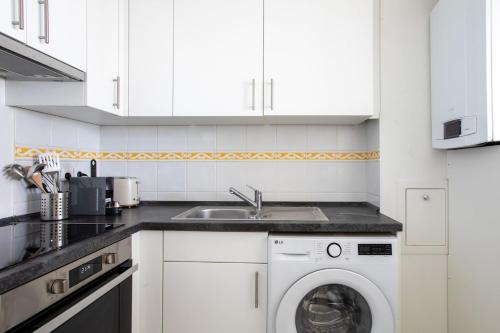 a kitchen with a washing machine and a sink at Appartement lumineux 3 frontières parking gratuit in Huningue