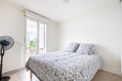 a white bedroom with a bed and a window at Appartement lumineux 3 frontières parking gratuit in Huningue