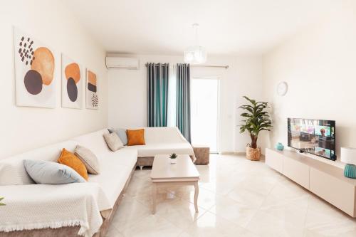 a white living room with a couch and a tv at CAPTAIN'S RESIDENCE in Ksamil