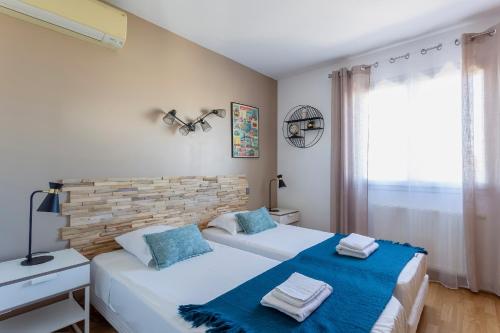 - une chambre avec 2 lits et des serviettes bleues dans l'établissement Villa Douce Vague - Le Grau du Roi, au Grau-du-Roi