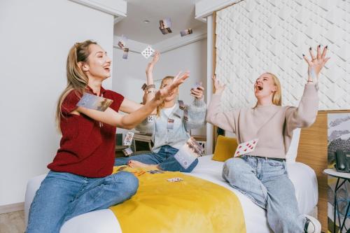 three women sitting on a bed with their hands in the air at New Hotel Piscine Wellness & Spa in Casablanca