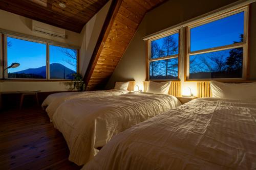two beds in a bedroom with two windows at Calm villa 富士山中湖 in Yamanakako
