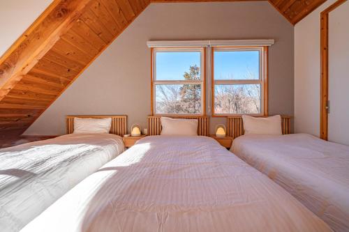 two beds in a room with a window at Calm villa 富士山中湖 in Yamanakako