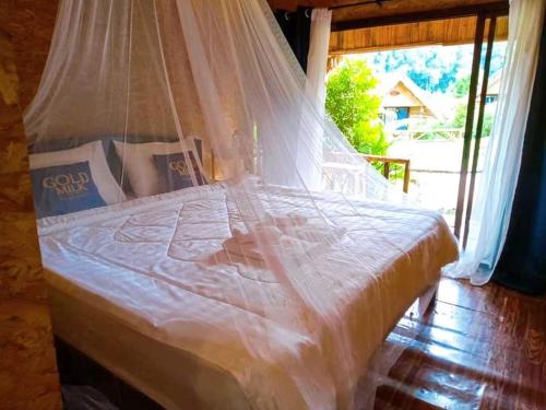 a bed with a mosquito net in a room with a window at 3 Pok Maewang jinxiang Gold elephant park in Ban Mae Sapok Noi