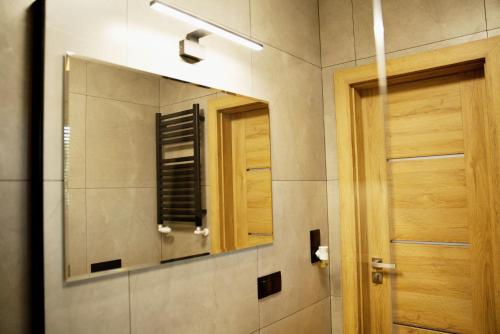 a bathroom with a mirror and a wooden door at Apartamenty na Zatorskiej by Housine in Zator