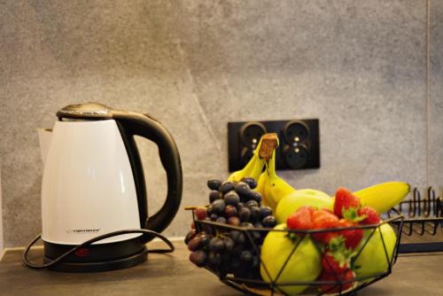 a bowl of fruit next to affeepot and a basket of fruit at Apartamenty na Zatorskiej by Housine in Zator