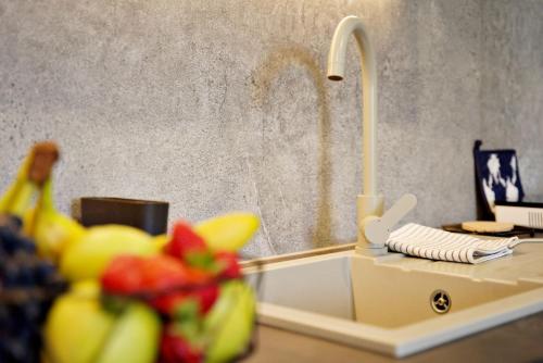 a kitchen counter with a sink with fruit on it at Apartamenty na Zatorskiej by Housine in Zator