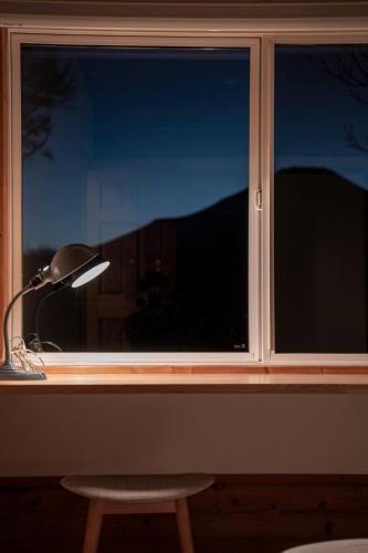 a window with a lamp and a chair in front of it at Calm villa 富士山中湖 in Yamanakako