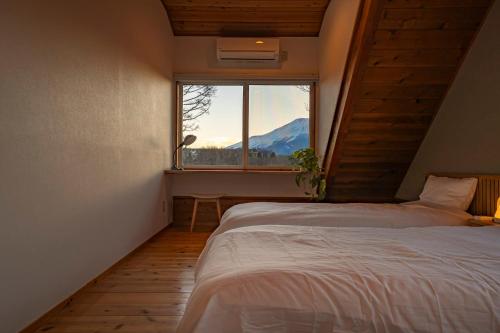 a bedroom with a bed and a window with a mountain at Calm villa 富士山中湖 in Yamanakako