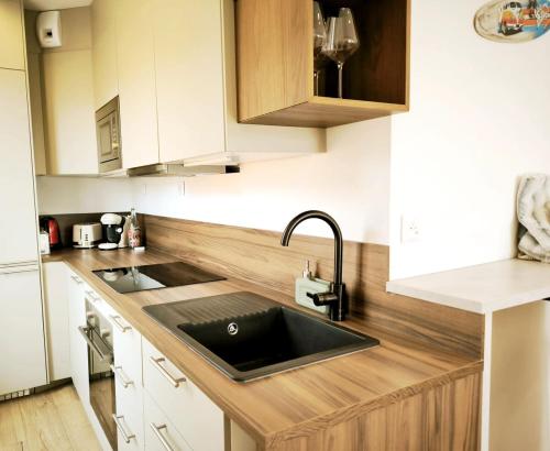 - une cuisine avec un évier noir et des placards en bois dans l'établissement Appartement rénové, 1 chambre, centre historique, à Hyères