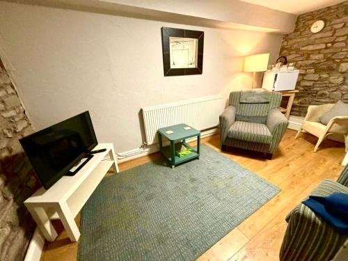 a living room with a tv and a chair at Kings Arms Hotel in Kirkby Lonsdale