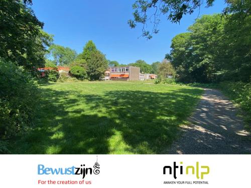 a large grassy field with a house in the background at Het Huis van Bewustzijn in Limmen