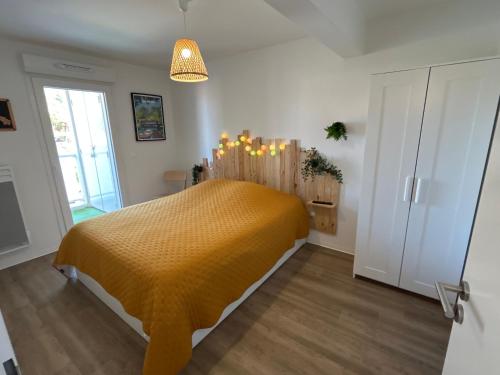 une chambre avec un lit avec un couvre-lit jaune dans l'établissement Au cœur de Lacanau Océan Appartement neuf avec parking, à Lacanau-Océan