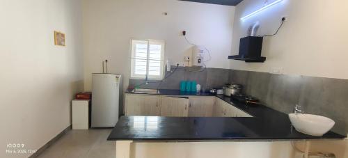 Una cocina con encimera negra y refrigerador. en VILLA RISHAAM with swimming pool, en Pondicherry