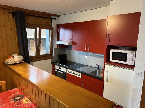 a kitchen with red cabinets and a sink and a microwave at Melezes K 010 - SKI & NATURE apartment 6 pers in Veysonnaz