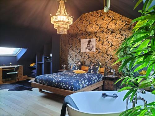a bedroom with a bed and a chandelier and a tub at Le Duché de Godefroy in Bouillon