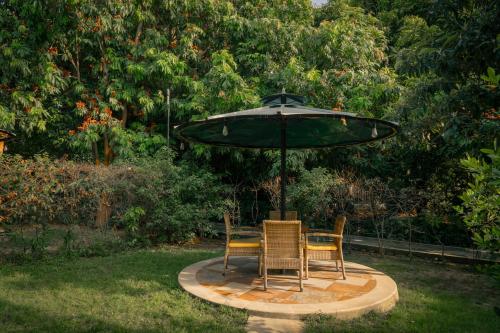 a table and two chairs under an umbrella at Aahana Resort - Jim Corbett in Rāmnagar
