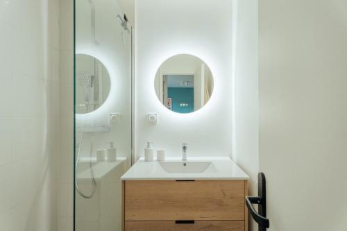 La salle de bains est pourvue d'un lavabo et de deux miroirs circulaires. dans l'établissement Les Terrasses de Venetis - parking for 3 people, à Vannes